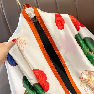 Elegant white silk scarf with vibrant gingko leaf patterns and orange borders