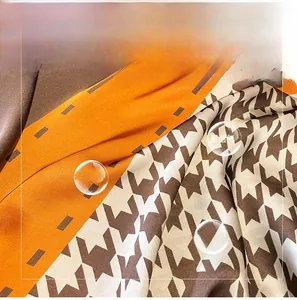 Detail of soft faux silk fabric showing orange geometric patterns and classic houndstooth