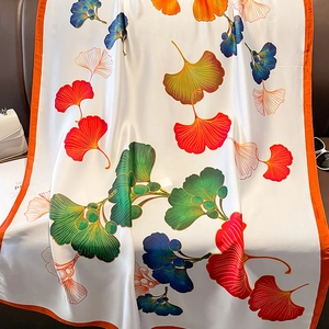 Elegant silk-like ginkgo leaf print scarf on leather sofa with luxury accessories
