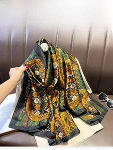 Detail of oversized silk scarf with vintage paisley and geometric patterns in deep green