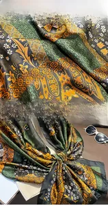 Close-up of emerald and gold paisley silk scarf showing meticulous hem stitching detail