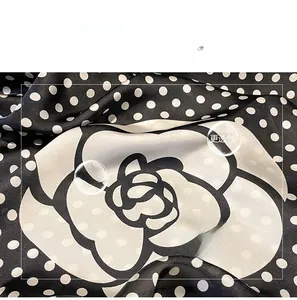 Macro detail of breathable black imitation silk fabric with white polka dots and floral print