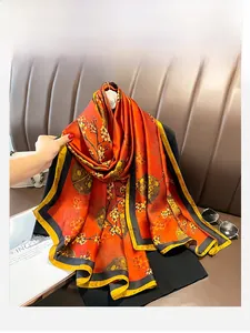 Détail d'un foulard en soie orange avec imprimé floral vintage et bordure contrastée