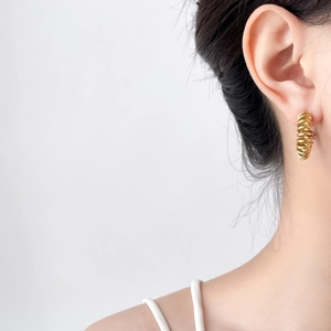 Gros plan détaillé de boucles d'oreilles spirales dorées portées avec finition brillante