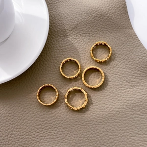 Dettaglio di cinque anelli a maglia placcati in oro 18K su superficie in pelle