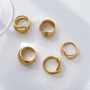 Detail of 18K gold plated hollow wide band and twisted rope rings on white background