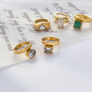 Close-up of geometric gold-plated rings set with green and clear zircon gemstones