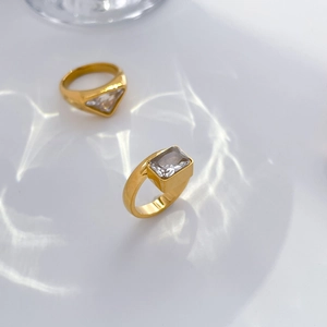 Macro detail of 18K gold-plated titanium rings with emerald-cut and triangle zircon