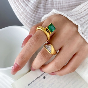 Macro detail of 18K gold-plated rings with square emerald and triangle zircon stones