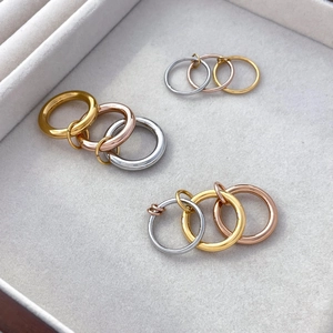 Macro detail of multi-tone interlinked rings in 18K gold, silver, and rose gold finishes