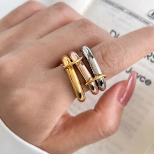 Close-up of interlocking tricolor 18K gold plated titanium rings on model's hand