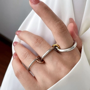 Macro detail of multi-linked 18K gold-plated titanium rings in tri-color metallic finish