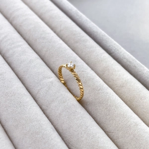 Close-up of golden twist band ring with round cubic zirconia in velvet jewelry box