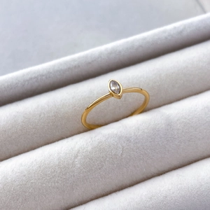 Macro shot of marquise-cut zircon ring on grey velvet, highlighting gold band detail