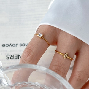 Close-up of gold twist rings with square and marquise zircons on a lifestyle background