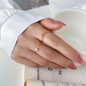 Detailed view of gold twist rings with square zircon and dangling round gem charm