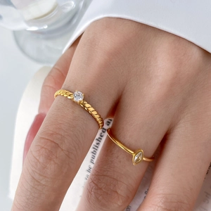 Detail of twisted gold ring with round zircon and marquise cut crystal band