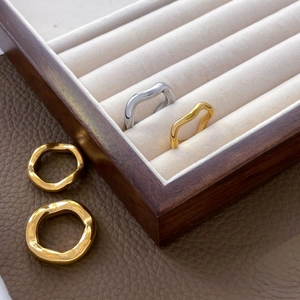 Detail of wavy stackable rings in gold and silver finish on a premium jewelry display