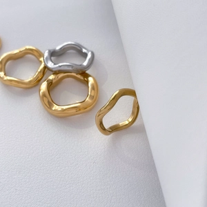 Macro view of organic wavy titanium steel rings in polished gold and silver finish