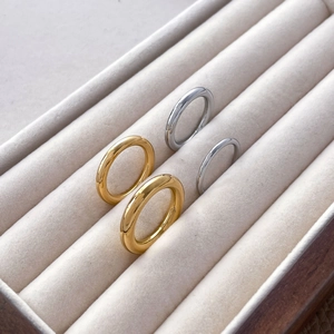 Close-up of minimalist gold and silver stacked bands on a beige jewelry tray