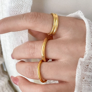 Detailed view of stacked 18K gold plated titanium rings on hand with knit texture background