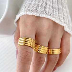 Macro detail of triple-layered gold-plated chunky wavy rings on a hand