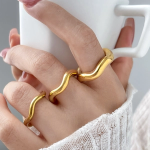 Detail of 18K gold plated wavy rings stacked on fingers with high polished finish