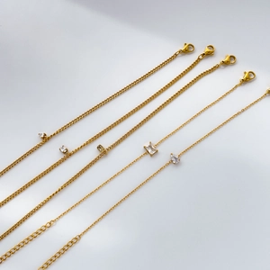 Détail de 5 bracelets en chaîne plaqués or avec divers pendentifs en zircone cubique