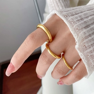 Close-up of stacked minimalist wavy 18K gold plated rings on hand with knit sweater