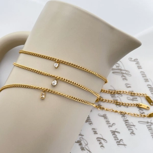 Détail de trois chaînes dorées 18K avec pendentifs en zircon cœur et ovales