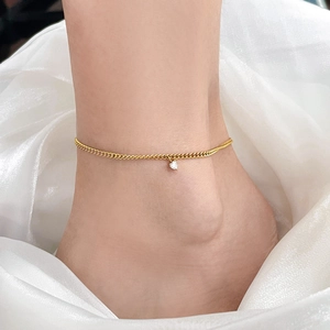 Gros plan d'une chevillère dorée avec pendentif cœur en zircon sur organza blanc