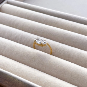 Detailed shot of a gold marquise-cut zircon ring on a grey velvet jewelry box display