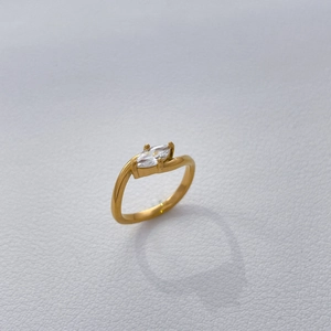 Detail of gold-plated titanium ring with marquise-cut zircon on white leather