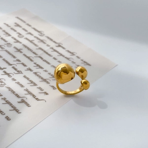 Détail macro d'une bague dorée en acier inoxydable avec trois sphères organiques