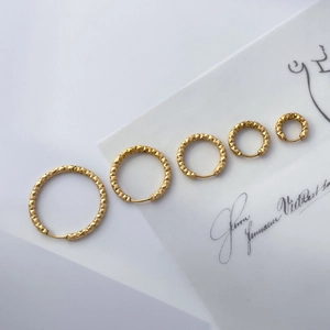 Détail de cinq créoles en titane plaqué or 18 carats aux motifs géométriques texturés
