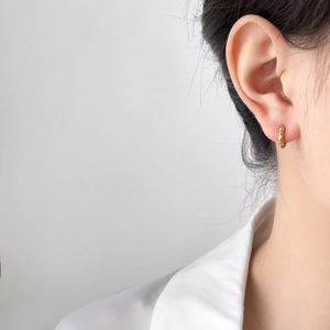 Gros plan détaillé de la boucle d'oreille en titane doré avec texture de pneu