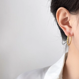 Boucles d'oreilles créoles en titane plaqué or 18K avec texture pneu sur mannequin