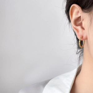 Gros plan de boucles d'oreilles créoles en titane doré avec texture pneu et cratères
