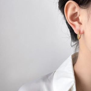 Gros plan de créoles plaquées or 18 carats avec texture de pneu sur l'oreille du mannequin