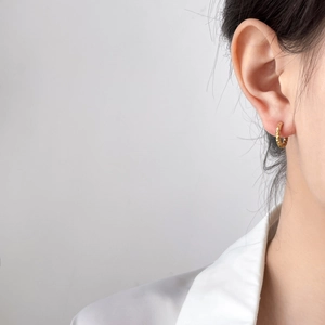 Gros plan d'une boucle d'oreille en titane doré 18 carats avec texture pneu sur l'oreille
