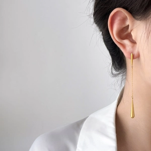 Elegant gold titanium steel long chain earrings featuring hollow teardrop pendants on model