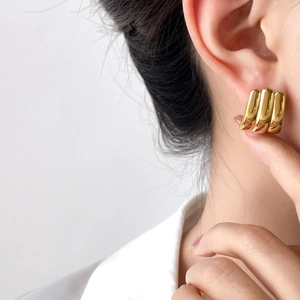 Close-up of polished gold triple-arc hoop earrings on a model for a modern minimalist look