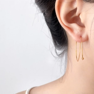 Close-up of minimalist 18K gold plated bead earrings worn on a model ear lobe