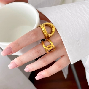 Détail de bagues ajourées plaquées or 18 carats sur un mannequin tenant une tasse