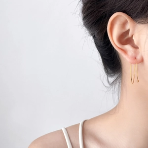 Close-up of minimalist double golden hoop earrings with bead detail on a female ear