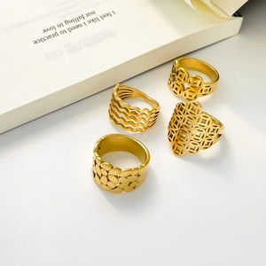 Golden stackable titanium steel rings with hollow wave and coin patterns on white book