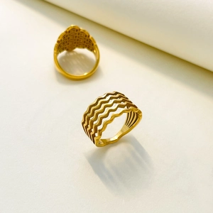 Detailed view of layered hollow wave rings with golden polished finish on a white background
