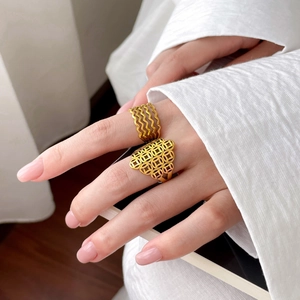Detail view of gold wave layered ring and hollow geometric pattern on model finger