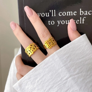 Gold-plated multilayer rings featuring coin cutouts and leaf textures on a model's hand