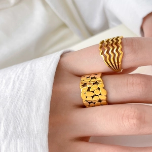 Detail of gold layered wave and textured leaf pattern rings on model hand